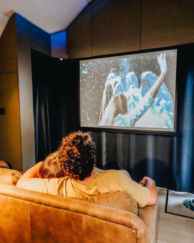 A couple watch a movie at SeaBeds Luxury Lookouts at Woodlands Glencoe.