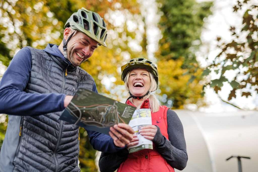 Couple laughing over map at Woodlands Glencoe, E-Bike hire in Glencoe, Scotland.