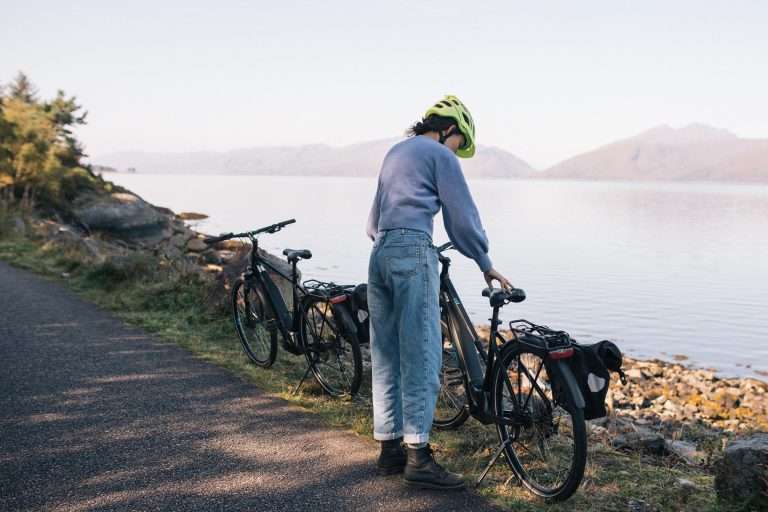 Roots 6 Woman on E-bike on Caledonia way cycle track, hired from Woodlands Glencoe, Scotland. Bike hire Glencoe