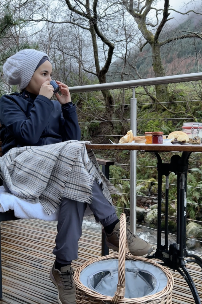 A lady enjoys breakfast on the terrace of RiverBeds Luxury Wee Lodges in Glencoe.