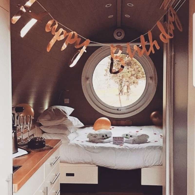RiverBeds Luxury Wee Lodges set up for a birthday celebration with happy birthday banner, balloons, birthday cake and prosecco.