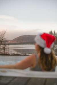 A lady in a Santa hat enjoys the hot tub at SeaBeds Luxury Lookouts in Glencoe.