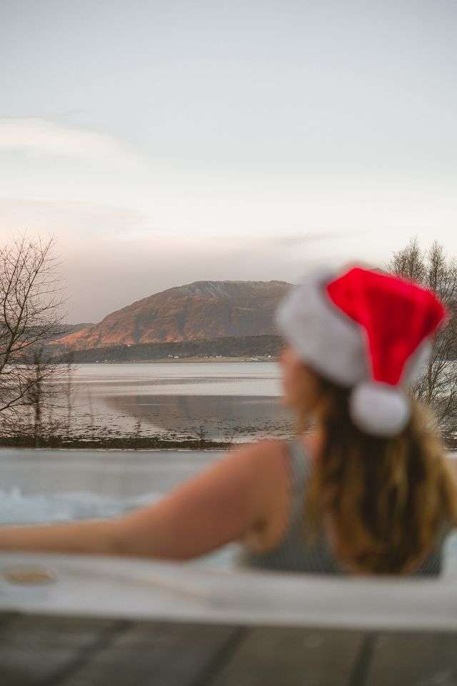 A lady in a Santa hat enjoys the hot tub at SeaBeds Luxury Lookouts in Glencoe.