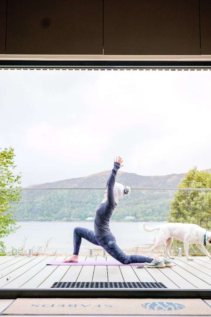 A lady does yoga on the terrace of SeaBeds Luxury Lookouts at Woodlands Glencoe.