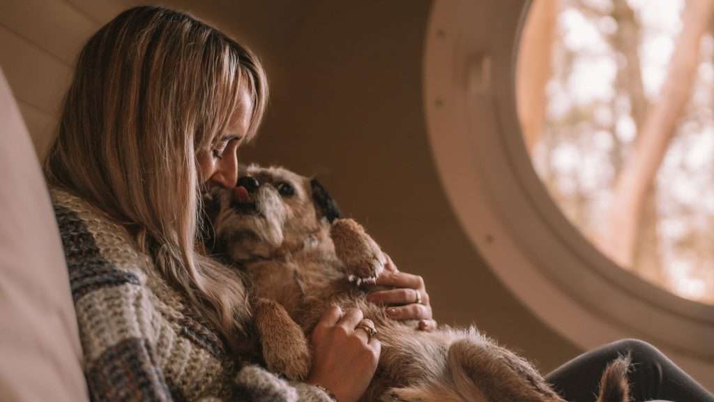 A woman gives her border terrier a cuddle at RiverBeds Luxury Wee Lodges in Glencoe.