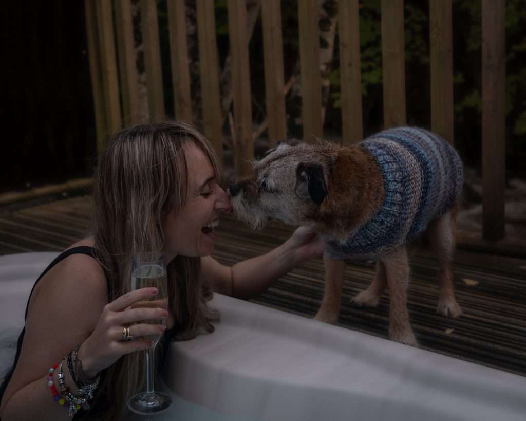 Woman in hot tub with dog at RiverBeds Luxury Wee Lodges at Woodlands Glencoe. Dog friendly luxury lodges in Glencoe.