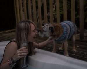Woman in hot tub with dog at RiverBeds Luxury Wee Lodges at Woodlands Glencoe. Dog friendly luxury lodges in Glencoe.