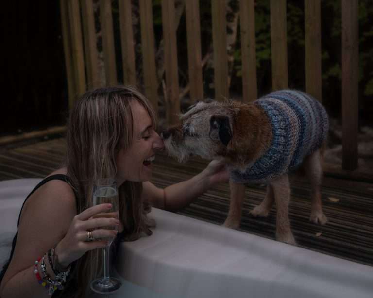Woman in hot tub with dog at RiverBeds Luxury Wee Lodges at Woodlands Glencoe. Dog friendly luxury lodges in Glencoe.