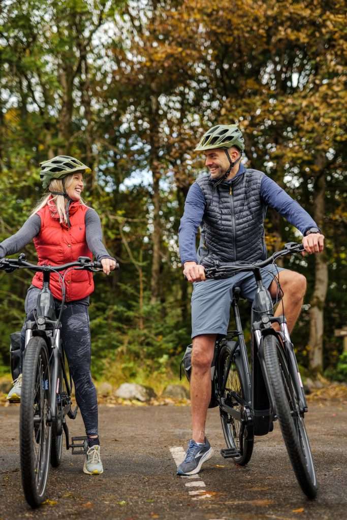 E-bike hire at Woodlands Glencoe Activity Centre is one of the most popular activities in Glencoe. A couple ride the Caledonia Way Cycle Track which runs from Ballachulish to Oban.