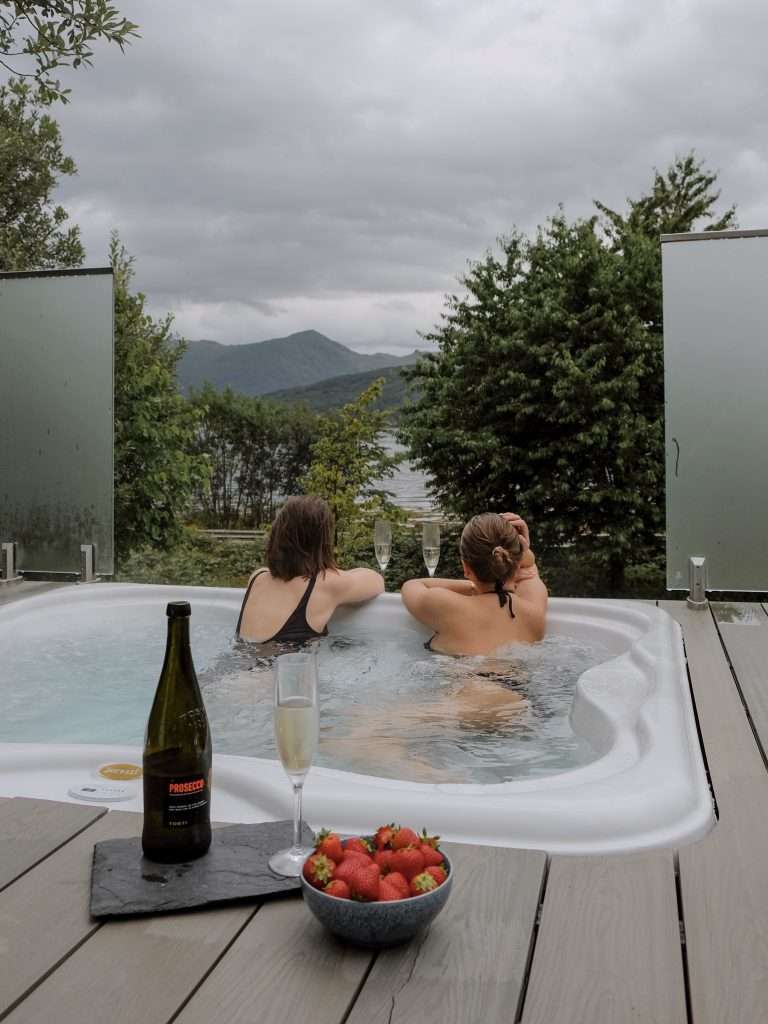 A hen weekend enjoying the loch and mountain view from the infinity hot tub at SeaBeds Luxury Lookout Lodges at Woodlands Glencoe. Extra romantic with prosecco and strawberries. Black Friday Deals in Glencoe.
