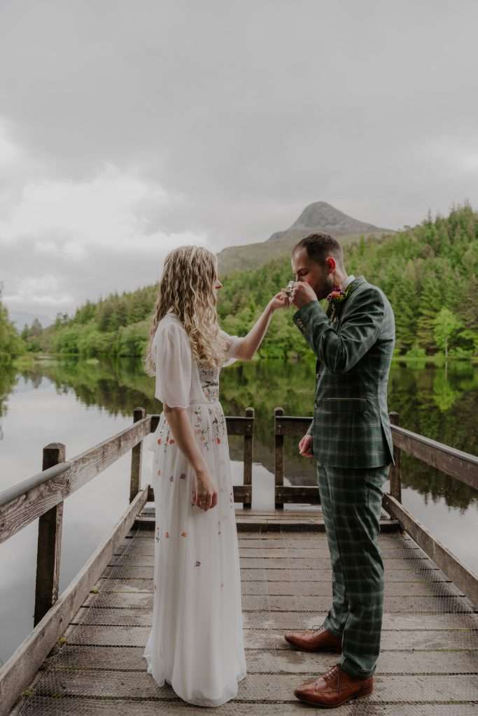 A couple take a drink from the quaich at Glencoe Lochan near Woodlands Glencoe.