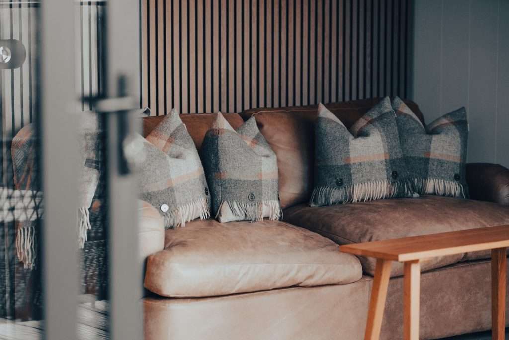 The comfortable Loaf sofa bed with tweed cushions in the living area of SeaBeds Luxury Lookout Lodges with Hot Tubs at Woodlands Glencoe in the Scottish Highlands.