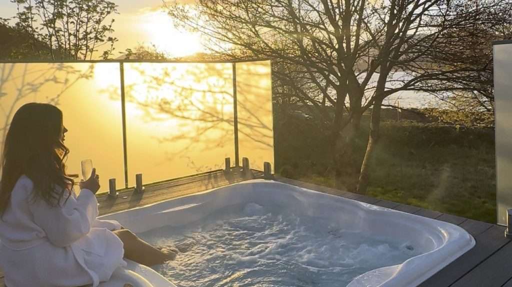 A lady relaxes in the hot tub of SeaBeds Luxury Lookouts after enjoying a treatment at Woodlands Wellness Studio.