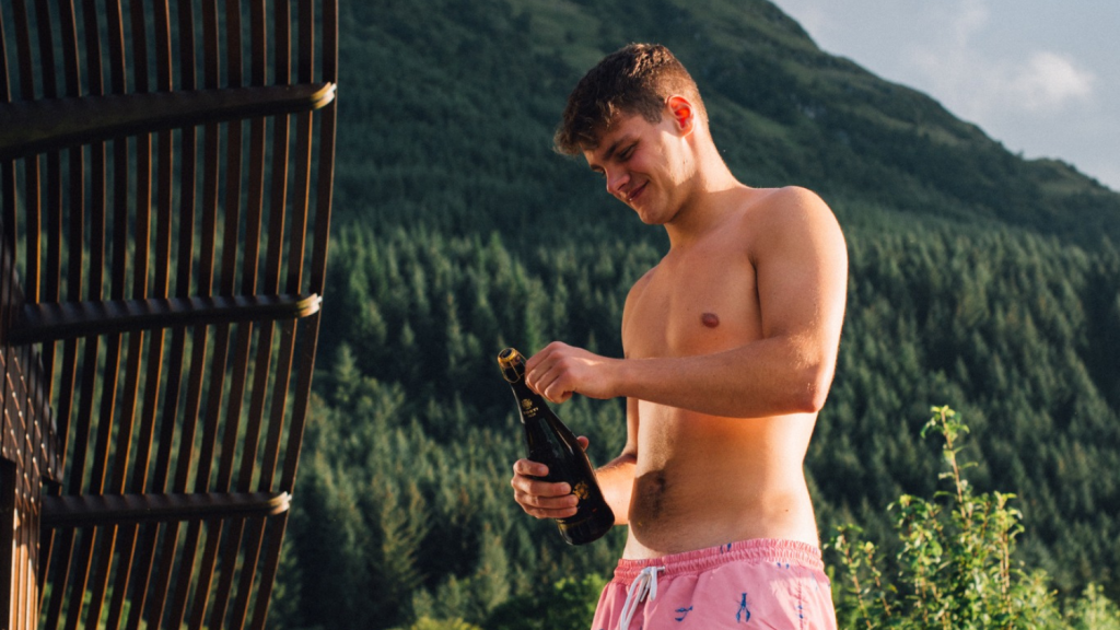 A man pops open the bubbles at SeaBeds Luxury Lookout Lodges at Woodlands Glencoe.