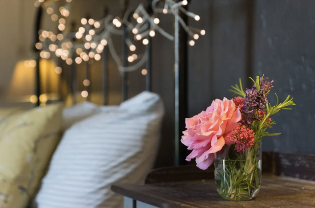 The king size bed with fresh flowers and fairy lights at the family and group friendly School House villa in Pujols, Aquataine, South West France.