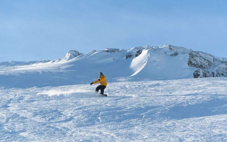 A snowboarded swishes down the slopes at Glencoe Mountain Resort. Skiing holidays at Woodlands Glencoe.