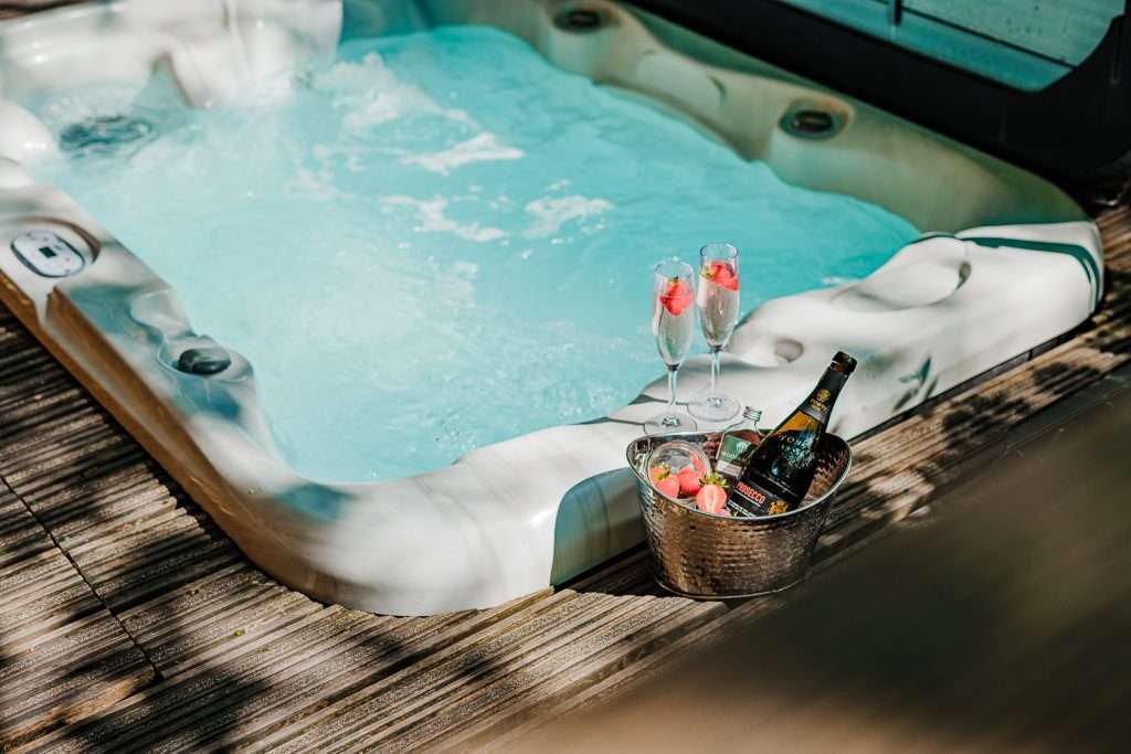 Sunken hot tub with champagne for two on the terrace of the romantic RiverBeds Luxury Wee Lodges with Hot Tubs at Woodlands Glencoe.